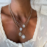 Gold faith necklace stack featuring white enamel Marian pendants