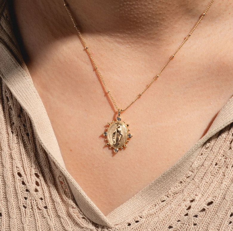 Lady Lourdes gold pendant necklace styled with layered jewelry