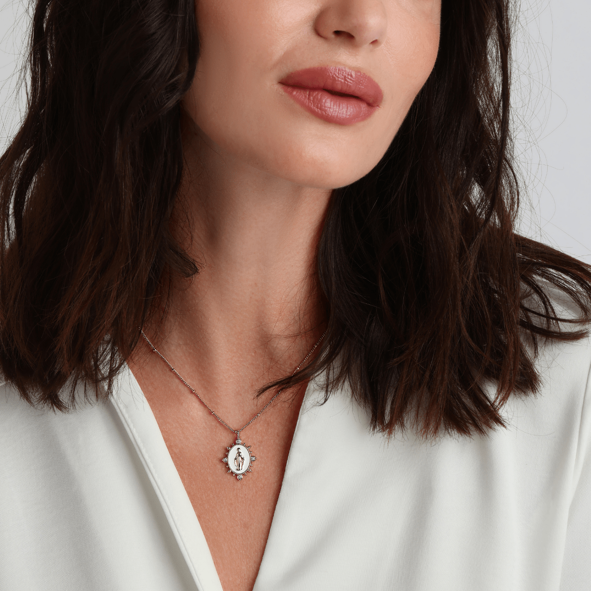 White Lady Lourdes necklace styled with layered gold jewelry